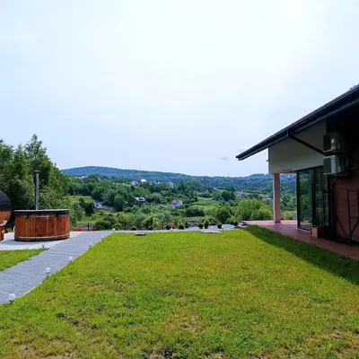 a large grassy field next to a building at ArPioNa dom nad jeziorem z jacuzzi, sauną i placem zabaw in Dąbrówka