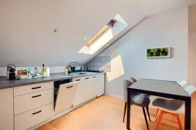 a kitchen with white cabinets and a table and a staircase at ArPioNa dom nad jeziorem z jacuzzi, sauną i placem zabaw in Dąbrówka