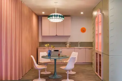 a kitchen with pink cabinets and a table and chairs at Pops Apartment in Kraków