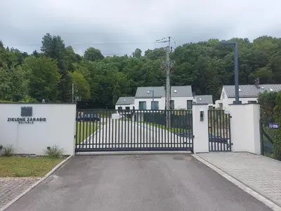 a gate to a driveway with houses and trees at Apartament na Osiedlu Zielone Zarabie in Myślenice