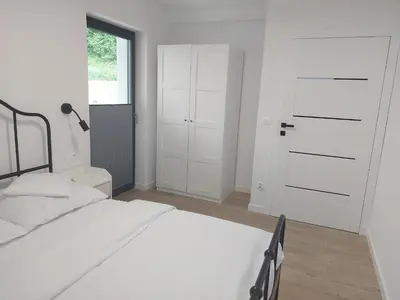 a white bedroom with a bed and a closet at Apartament na Osiedlu Zielone Zarabie in Myślenice