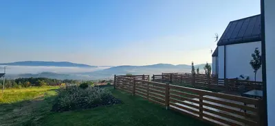 a fence on the side of a house with mountains in the background at Lipowe Apartmenty in Limanowa