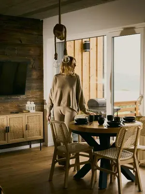 a woman sitting at a table in a living room at Lipowe Apartmenty in Limanowa