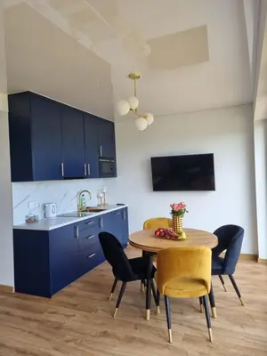 a kitchen with blue cabinets and a table and chairs at Lipowe Apartmenty in Limanowa