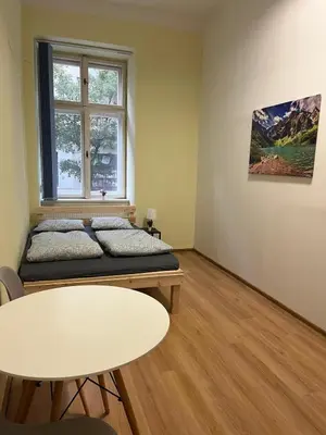 a room with a bed and a table and a window at Batorego Lovely Rooms in Kraków