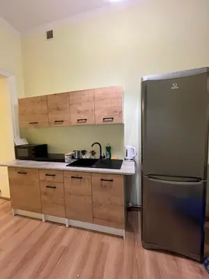 a kitchen with a stainless steel refrigerator and wooden cabinets at Batorego Lovely Rooms in Kraków