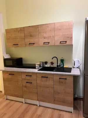 a kitchen with wooden cabinets and a sink and a refrigerator at Batorego Lovely Rooms in Kraków