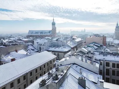 a city with snowy roofs and a clock tower at Jana Apartments in Kraków