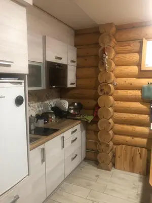 a kitchen with white cabinets and a wall of wood at Ranczo Borówka in Łapanów