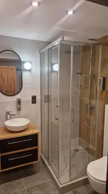a bathroom with a glass shower and a sink at Amazing Cracow Apartments in Kraków