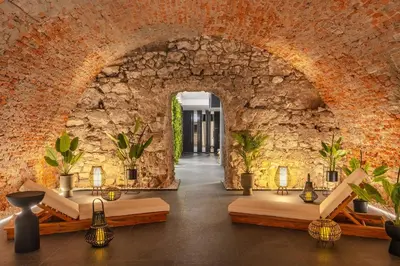 an archway in a stone wall with tables and lamps at Muse by StayLab in Kraków