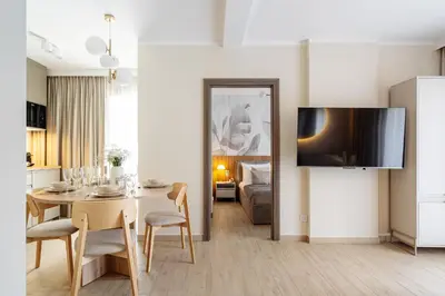 a dining room with a table and a tv on a wall at Muse by StayLab in Kraków