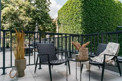 a balcony with chairs and a table and a hedge at Muse by StayLab in Kraków