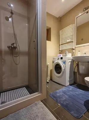 a bathroom with a shower and a washing machine at L-2 Kraków Center Studio O&P ApartFamily in Kraków