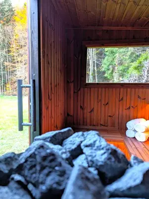 a wooden cabin with a window and a pile of rocks at Babia Ostoja - domek z balią i sauną in Zawoja