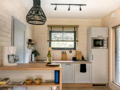 a kitchen with white cabinets and a pendant light at Babia Ostoja - domek z balią i sauną in Zawoja