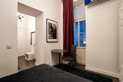 a bedroom with a bed and a table and a window at Piasek Elegant Apartments in Kraków