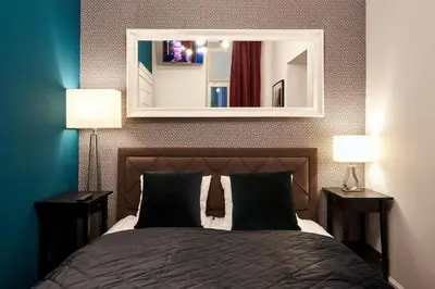 a bedroom with a bed with two lamps and a mirror at Piasek Elegant Apartments in Kraków