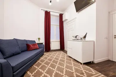 a living room with a blue couch and a kitchen at Piasek Elegant Apartments in Kraków