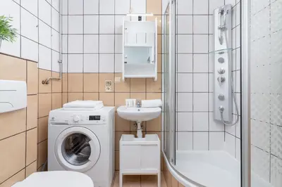 a bathroom with a washing machine and a sink at Comfy & Bright Studio Wielicka in Krakow by Noclegi Renters in Kraków
