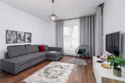 a living room with a gray couch and a tv at Zabłocie Pet-friendly Ślusarska Apartment by Noclegi Renters in Kraków