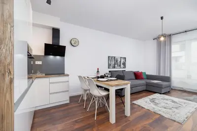 a kitchen and living room with a table and a couch at Zabłocie Pet-friendly Ślusarska Apartment by Noclegi Renters in Kraków