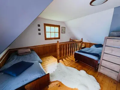 a attic bedroom with two beds and a staircase at Domek pod Modrzewiem in Nowy Targ
