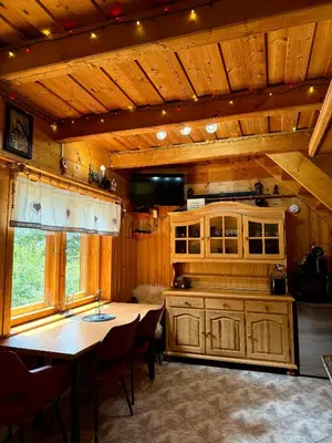 a kitchen with a table and a wooden ceiling at Domek pod Modrzewiem in Nowy Targ