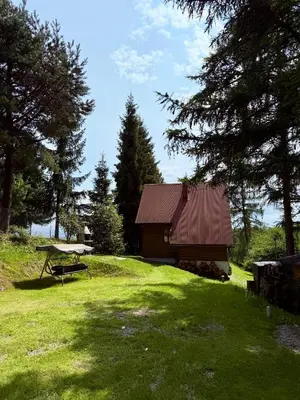 a cabin in a field with a picnic table in front of it at Domek pod Modrzewiem in Nowy Targ