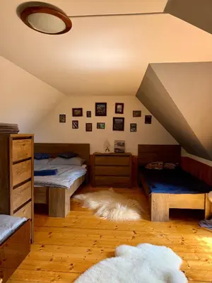 a attic room with two beds and a rug at Domek pod Modrzewiem in Nowy Targ