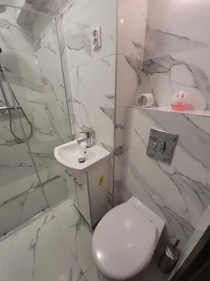 a white bathroom with a toilet and a sink at Apartamenty Kącik in Kraków