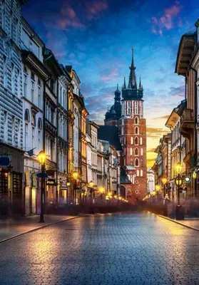 a city street at night with a clock tower at Apartamenty Kącik in Kraków