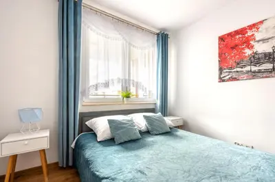 a bedroom with a bed with blue curtains and a window at Apartment BLUE PEARL 2 rooms Down Town 4 persons balcony free parking in Kraków
