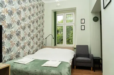 a bedroom with a bed and a chair and a window at Studio Asnyka Old Town in Kraków