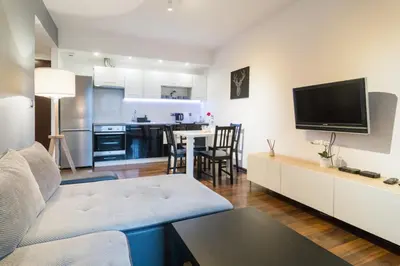 a living room with a couch and a tv and a kitchen at Romanowicza 5 Serene Place in Kraków
