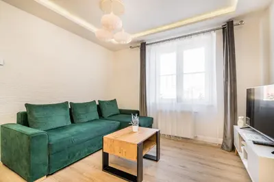 a living room with a green couch and a television at Apartament Na Szlaku WAWELOFTS in Kraków