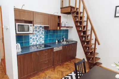 a kitchen with wooden cabinets and a spiral staircase at Kraków Wawel Zwierzyniecka in Kraków