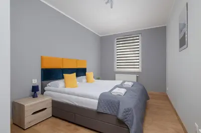 a bedroom with a large bed with yellow and blue pillows at Osiedle Avia Family Apartment in Kraków with Balcony by Noclegi Renters in Kraków