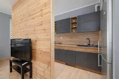 a kitchen with wooden walls and a tv in a room at Osiedle Avia Family Apartment in Kraków with Balcony by Noclegi Renters in Kraków