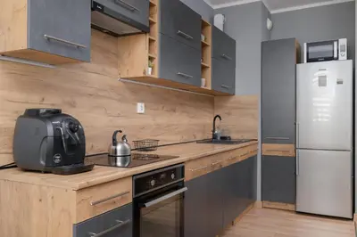 a kitchen with a sink and a refrigerator at Osiedle Avia Family Apartment in Kraków with Balcony by Noclegi Renters in Kraków