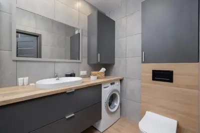 a bathroom with a sink and a washing machine at Osiedle Avia Family Apartment in Kraków with Balcony by Noclegi Renters in Kraków