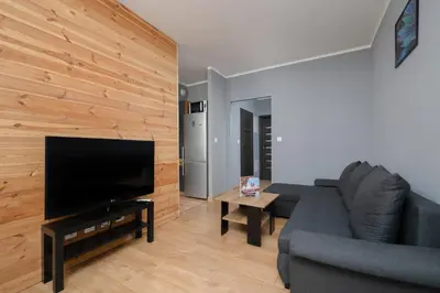 a living room with a couch and a flat screen tv at Osiedle Avia Family Apartment in Kraków with Balcony by Noclegi Renters in Kraków