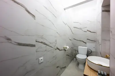 a bathroom with white marble walls and a toilet at Bracka Main Square Apartments in Kraków