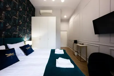 a bedroom with a large bed with white sheets and blue pillows at Bracka Main Square Apartments in Kraków