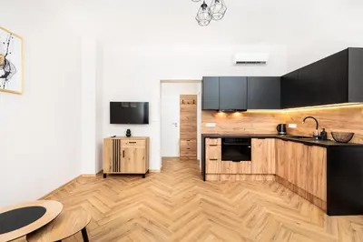 a kitchen with black cabinets and a wooden floor at City of the Kings-Poselska 24 in Kraków