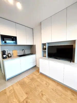a kitchen with white cabinets and a flat screen tv at Royal Smart Apartments Cracow in Kraków