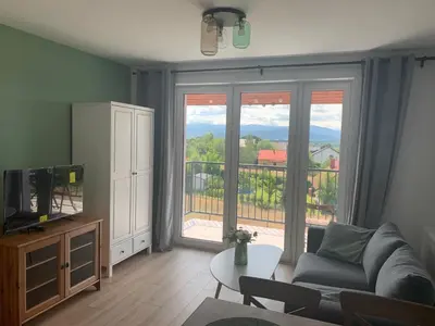 a living room with a couch and a large window at Apartament Smile in Tomice