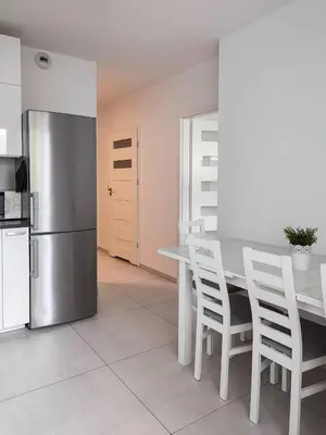 a kitchen with a table with white chairs and a refrigerator at Apartment Szwed-Sniadowskiej Residence in Kraków