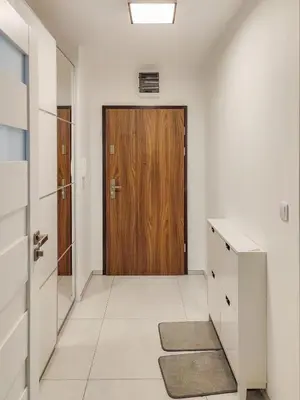 a hallway with a wooden door and a tile floor at Apartment Szwed-Sniadowskiej Residence in Kraków