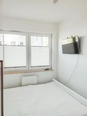 a white bedroom with a bed and two windows at Apartment Szwed-Sniadowskiej Residence in Kraków